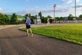 Concept of sports and health - teen boy runs along the stadium track, a soccer field with green grass Royalty Free Stock Photo