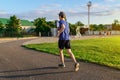 Concept of sports and health - teen boy runs along the stadium track, a soccer field with green grass Royalty Free Stock Photo