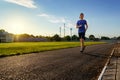 Concept of sports and health - teen boy runs along the stadium track, a soccer field with green grass Royalty Free Stock Photo