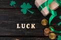 Concept for St. Patrick's Day. The word luck, clover shamrock and gift with a green ribbon on a dark wooden Royalty Free Stock Photo