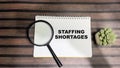 Concept of Staffing Shortages write on book isolated on Wooden Table Royalty Free Stock Photo