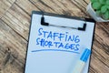 Concept of Staffing Shortages write on paperwork isolated on Wooden Table Royalty Free Stock Photo