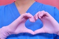 Concept of stay home, hands folded in the shape of a heart. Doctor in protective pink gloves and medical uniform, close-up