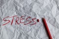 The concept of stress reduction. The word stress is written in red pencil on white crumpled paper.