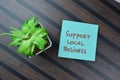 Concept of Support Local Business write on sticky notes isolated on Wooden Table