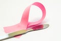 Concept surgery treatment or plastic of breast. Pink ribbon as symbol of breast pathology, lies next to surgical scalpel. Photo fo Royalty Free Stock Photo