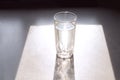 The concept of taking water during the day. A glass of water on a gray kitchen table in the rays of the outgoing sun, shadows from Royalty Free Stock Photo