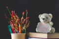 Concept of Teacher's Day. Objects on a chalkboard background. Books, green apple, bear with a sign: Happy Teacher's Day, pencils