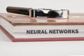 The concept of technology and development. Phrase, words, text NEURAL NETWORKS on the end of the book, a close-up front