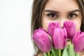 Cropped shot of cute girl with a bouquet of tulips looking with pleasure and her eys smiling.