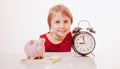 Concept: time is money. Cute little child girl holding a clock and piggy bank Royalty Free Stock Photo