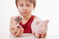 Concept: time is money. Humorous portrait of cute little business child girl holding a sand clock and piggy bank. Horizontal image Royalty Free Stock Photo