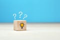 Concept of to find a creative idea or problem solving. Question mark and light bulb icons on wooden cube