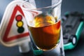 Concept on the topic of driving while intoxicated. A glass of whiskey and an inverted car