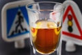 Concept on the topic of driving while intoxicated. Glass of whiskey and traffic signs