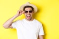 Concept of tourism and holidays. Close-up of happy man in summer hat and sunglasses enjoying vacation, standing over Royalty Free Stock Photo