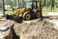 Concept of the tractor, the tractor digs and buries a trench for laying water on a forest plot for the construction of the house. Royalty Free Stock Photo