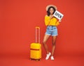 Concept of travel. happy black woman   with suitcase   points to a sign that says open on a colored  red background Royalty Free Stock Photo