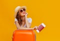 Concept of travel. happy woman girl with suitcase and passport on yellow background