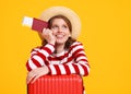 Concept of travel. happy young woman with suitcase and passport on yellow background