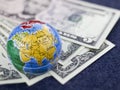 Concept of travel, small globe on background of dollars