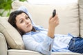 Crop. Bored and relaxed woman is watching TV, laying on a sofa. Close up.