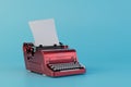 the concept of typed text on a typewriter. a red typewriter with a sheet of paper on a blue background. 3D render Royalty Free Stock Photo