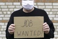 Concept unemployment and coronavirus a man in a medical hygienic mask is holding a cardboard tablet with a inscription