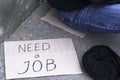 Concept unemployment, poverty, job search, next to an unemployed person sitting on the ground is the hat for alms and a cardboard