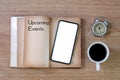 Concept Upcoming Events message on old notebook with phone, coffee cup on wooden table