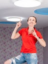 Concept update of the ceiling lamp in the children& x27;s room. A happy Woman on a stepladder points to the ceiling.