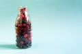The concept of using quick-frozen berries. A mixture of frozen black and red berries in a transparent bottle Royalty Free Stock Photo