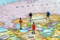 Miniature backpackers standing on a map of the world.