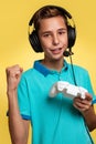 The concept of virtual and computer games. A teenage boy in a blue t-shirt and headphones, with a joystick in his hands, playing Royalty Free Stock Photo