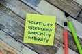 Concept of Volatility, Uncertainly, Complexity, Ambiguity write on sticky notes isolated on Wooden Table Royalty Free Stock Photo