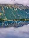 The concept of walking and eco-tourism. Explore the beauty of earth. A headland in the middle of the lake. Reflection of peaks of Royalty Free Stock Photo