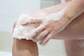 Woman soaps her leg with a bath sponge, naked wet girl in bathroom Royalty Free Stock Photo