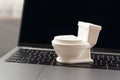 Concept of waste of time or busywork. Small toy white toilet bowl on laptop keyboard Royalty Free Stock Photo