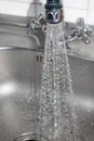 Concept water saving at home, reducing use. Water tap with flowing water with spray. Selective focus Royalty Free Stock Photo