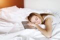 Young freelance woman tired of work fall asleep at laptop on bed white linen at home Royalty Free Stock Photo