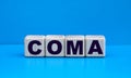 concept word COMA on cubes on a blue background Royalty Free Stock Photo