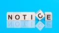 Concept word forming with cube on wooden desk background - Notice. Blue background