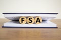 Concept word `FSA, flexible spending account` on wooden circles between pages of a book on a beautiful wooden table. White Royalty Free Stock Photo