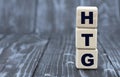 Concept of the word HTG on cubes on a wooden gray background Royalty Free Stock Photo