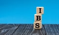 Concept word IBS on wooden cubes on a blue background
