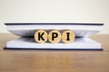 Concept word `KPI - key perfomance indicator` on wooden circles between pages of a book on a beautiful wooden table. White