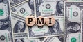 Concept word `PMI - purchasing managers index` on wooden circles on a beautiful background from dollar bills. Business concept