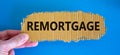 The concept word 'remortgage' on the piece of cardboard between fingers. Beautiful blue background copy spac