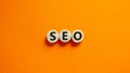 Concept word `SEO` on wooden circles on a beautiful orange background. Search engine optimization. Copy space Royalty Free Stock Photo