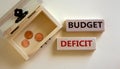 Concept words `budget deficit` on blocks on a beautiful white background, small chest with coins. Business concept, copy space Royalty Free Stock Photo